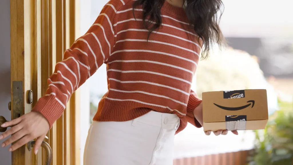 Femme recevant un colis Amazon à sa porte — illustration article théâtre Jeff Bezos Nice