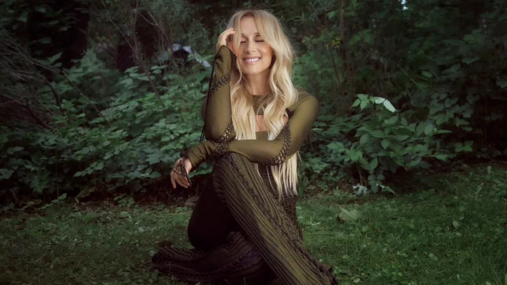 Lara Fabian souriante en robe verte dans un décor de verdure photo promotionnelle album Je suis là