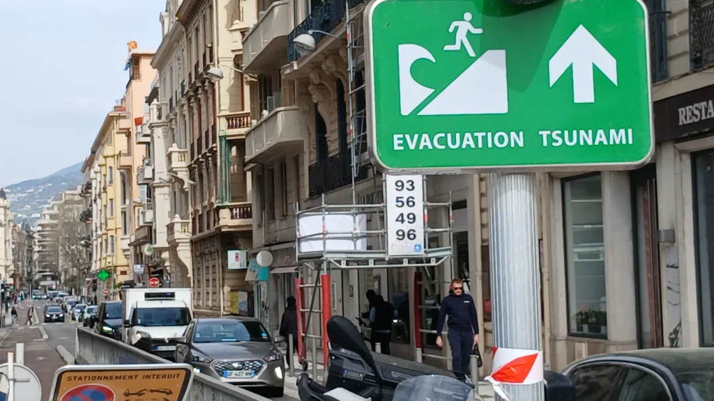 Panneau évacuation tsunami à Nice, rue avec circulation et immeubles haussmanniens