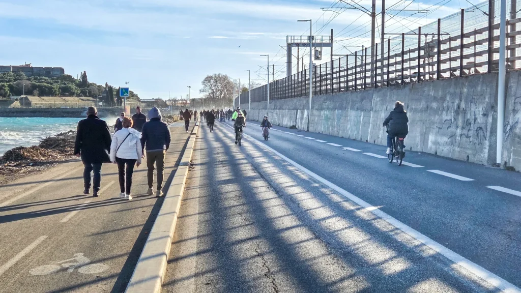 Promeneurs et cyclistes sur le bord de mer piéton à Antibes, Fort Carré en arrière-plan