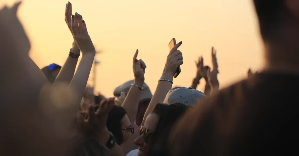 Concert en plein air mains levees coucher de soleil ambiance festival