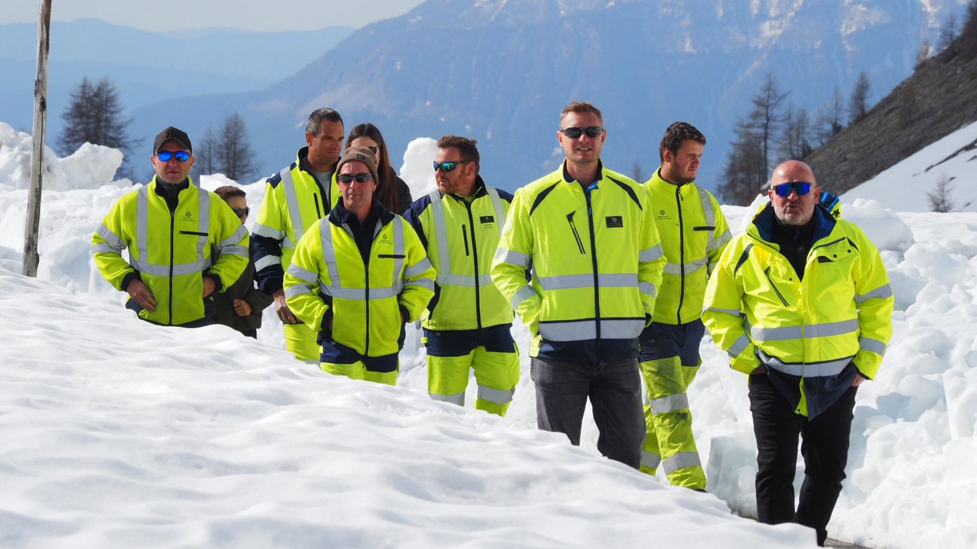 Agents du Département en parka jaune marchant sur la route déneigée du col de la Cayolle
