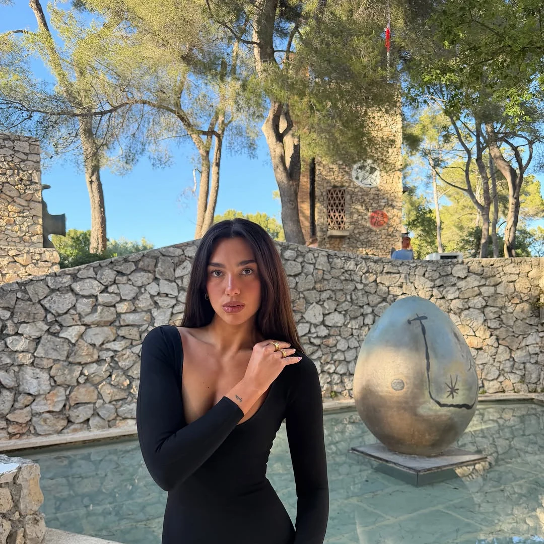 Portrait de Dua Lipa devant l'œuf-sculpture de Miró et la Tour Sert