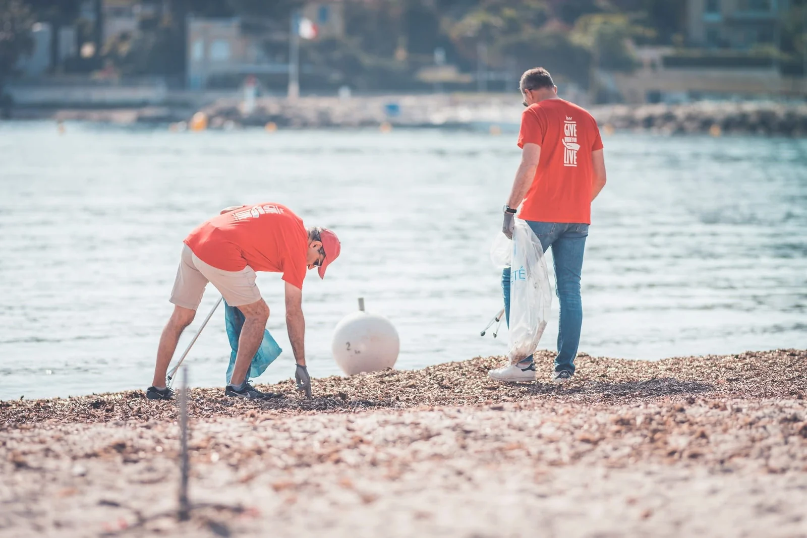Deux bénévoles ramassent les déchets au bord de l'eau à Antibes