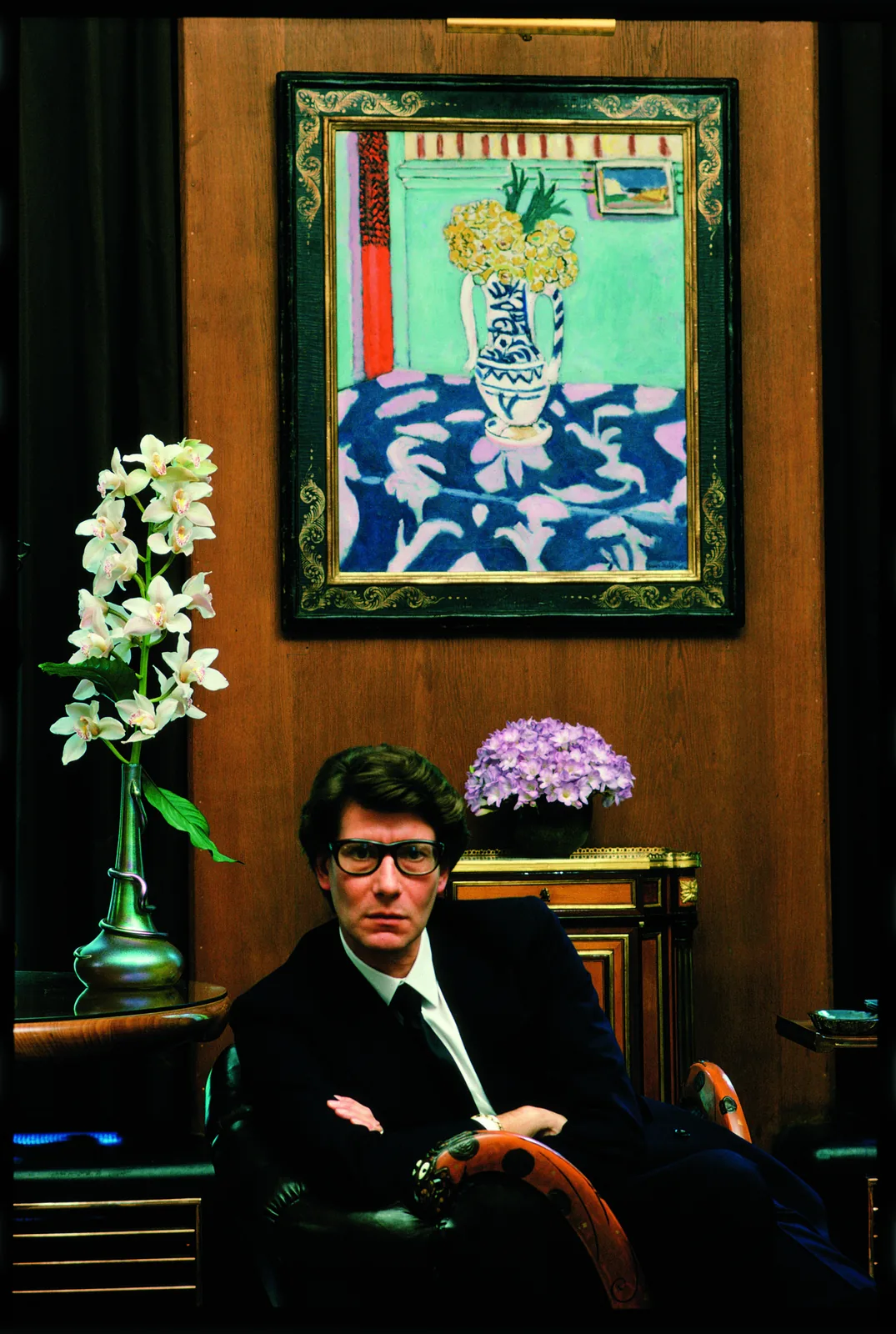 Yves Saint Laurent assis sous un tableau de fleurs de Matisse, Paris, 1983