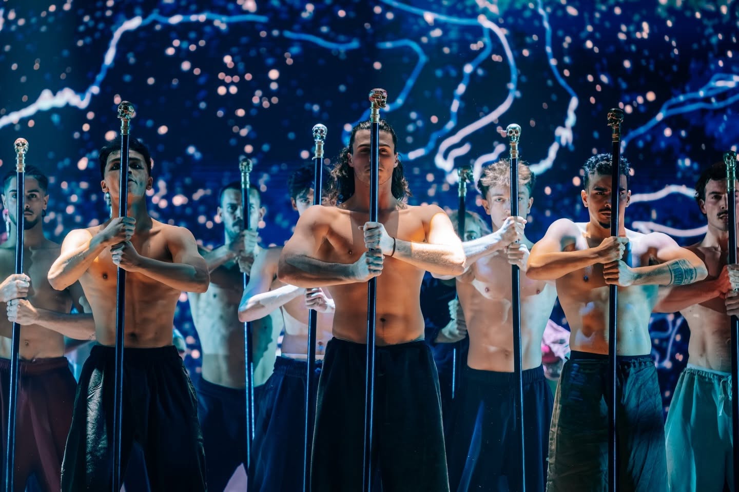 Danseurs torse nu tenant des épées devant un ciel bleu dans Le Roi Soleil
