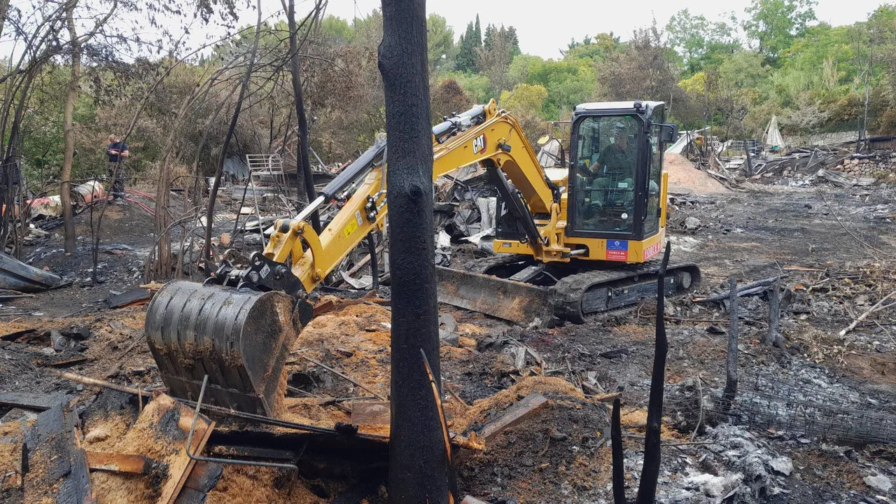 Pelleteuse jaune deblayant des decombres calcines apres un incendie dans les Alpes-Maritimes