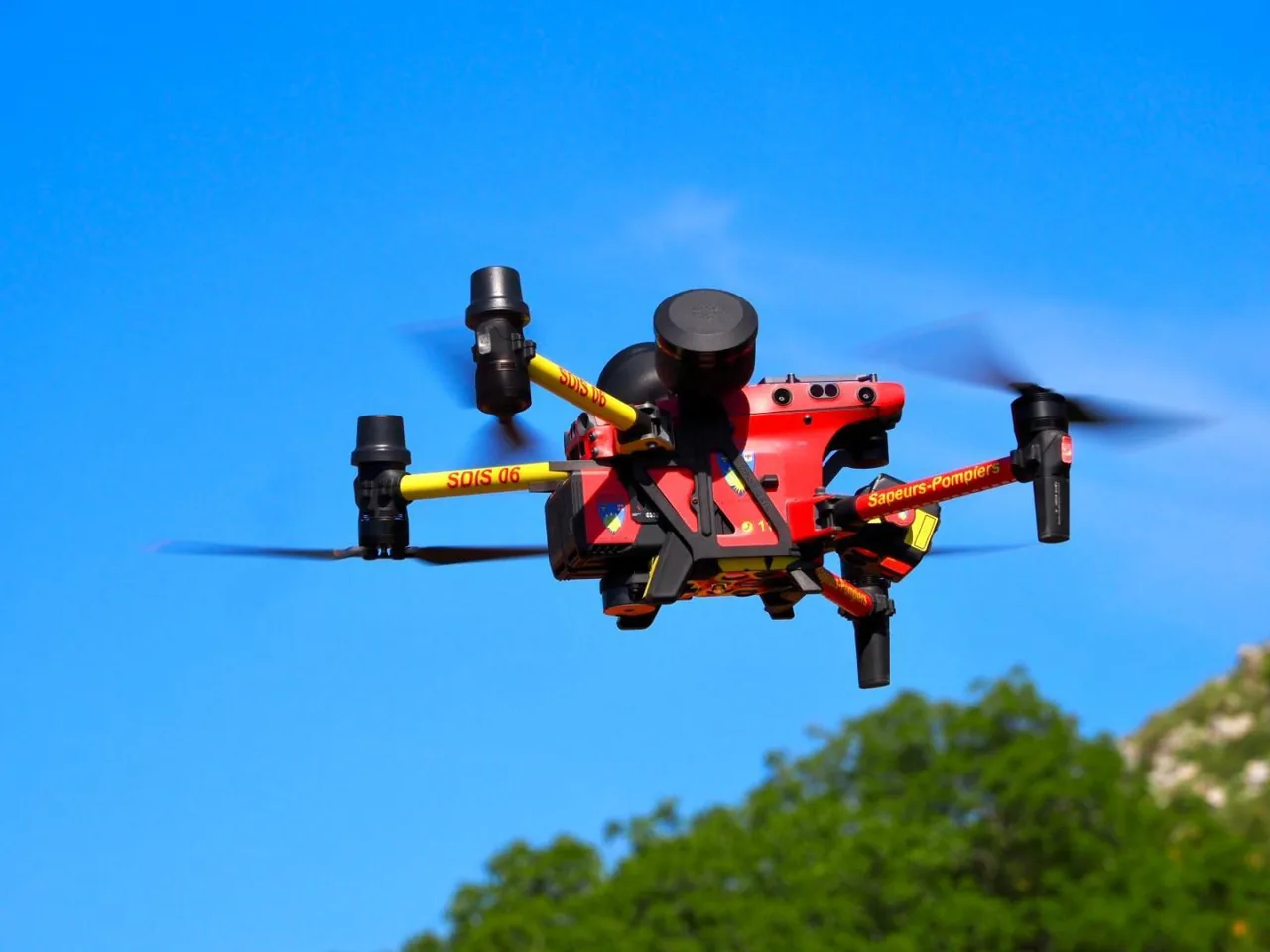 Drone rouge et jaune des sapeurs-pompiers SDIS 06 en vol dans un ciel bleu