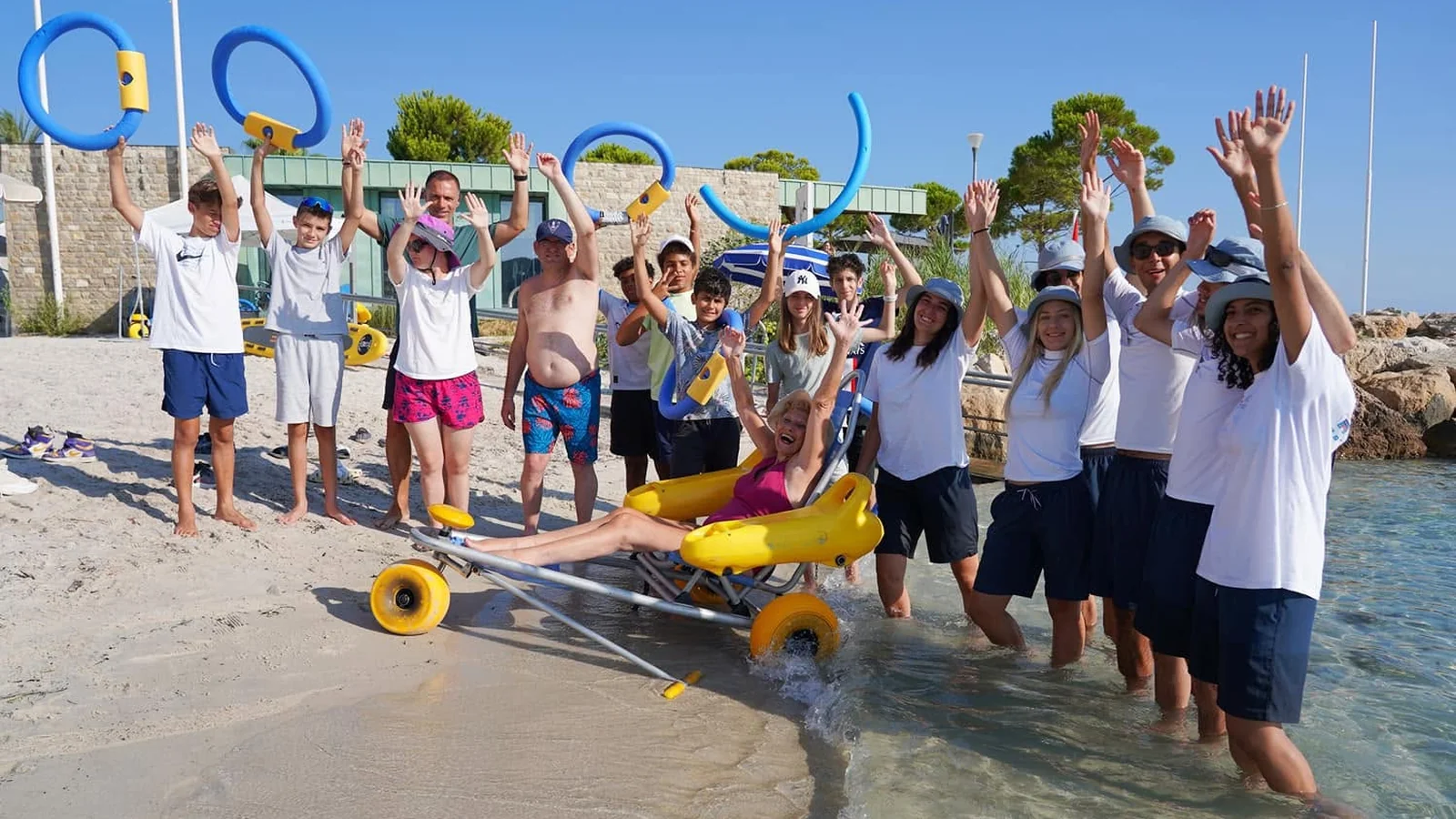 Baigneurs et handiplagistes lèvent les bras de joie autour d'un tiralo à la handiplage de la Salis, Antibes