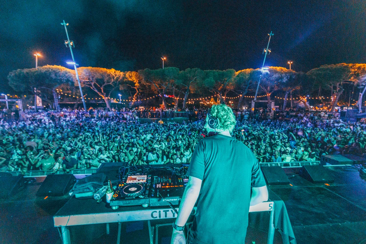 DJ de dos aux platines face à une foule compacte de nuit aux Nuits Carrées