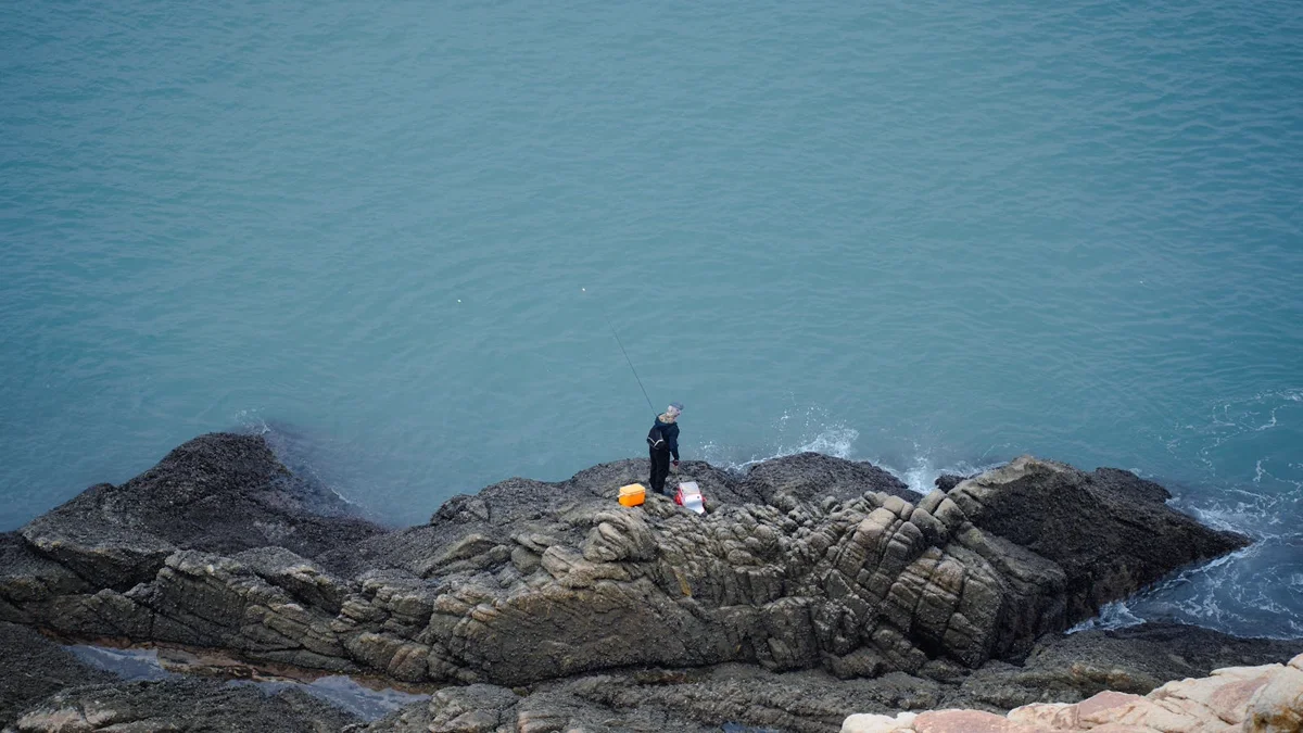 Pêcheur à la ligne sur des rochers en bord de mer