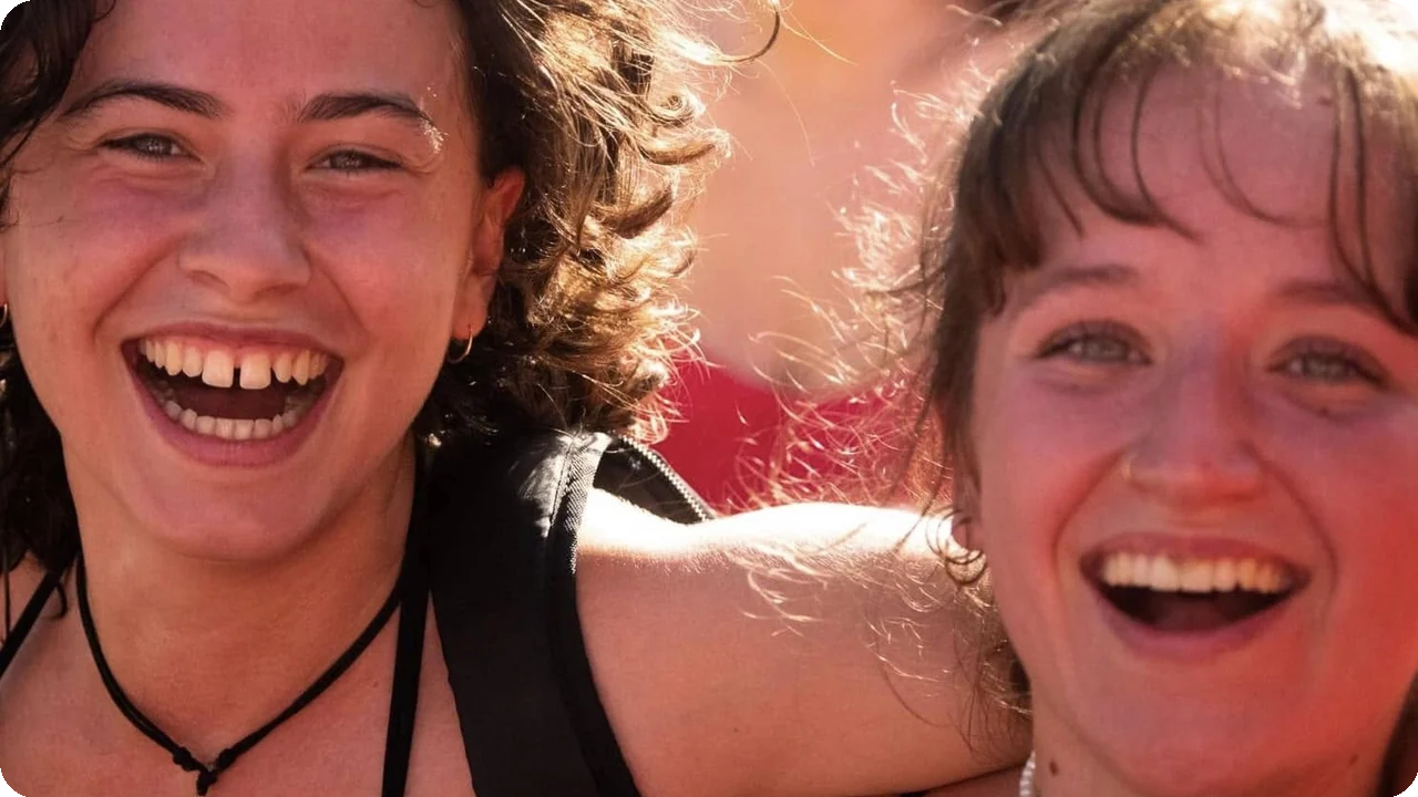 Deux jeunes femmes rient lors de la Pink Parade de Nice au soleil couchant