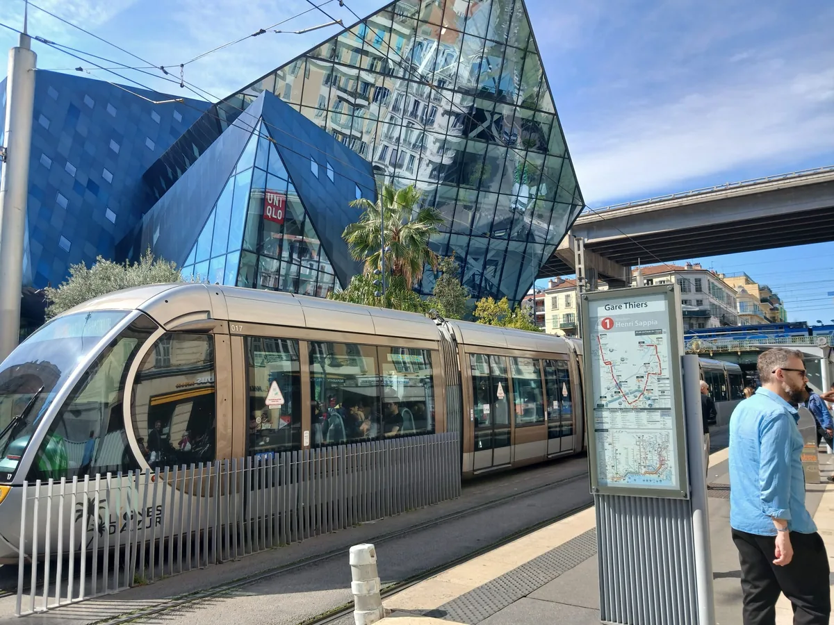 Tram à l’arrêt Gare Thiers devant le bâtiment de verre, à côté de la gare de Nice-Ville