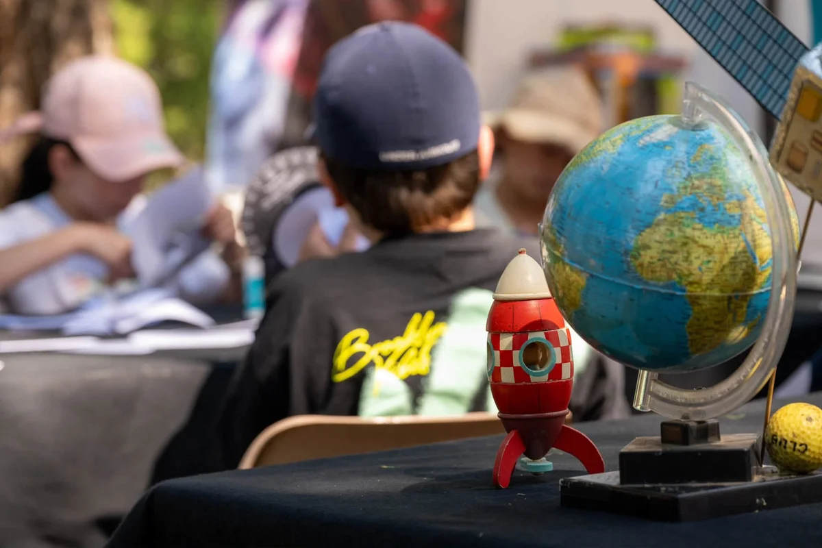 Globe terrestre et fusée en bois sur une table d'atelier du festival AstroValberg