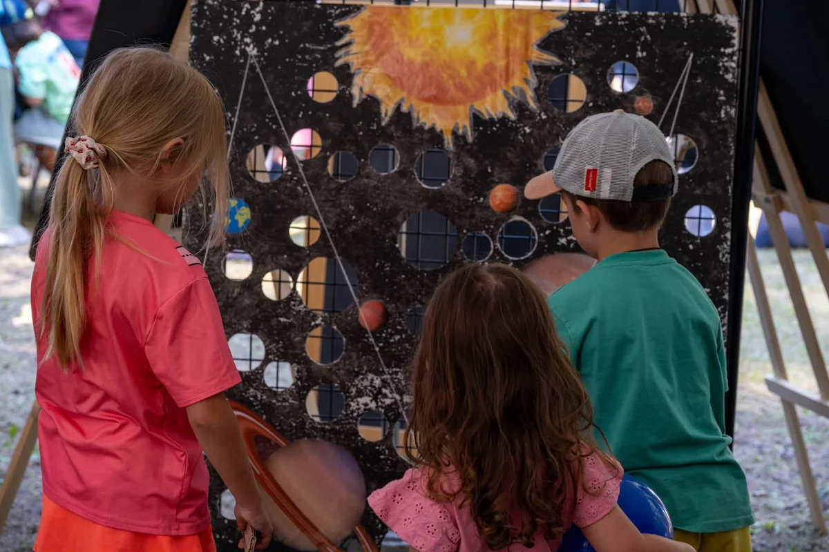 Trois enfants devant un jeu d'adresse sur le système solaire au Village Astro de Valberg