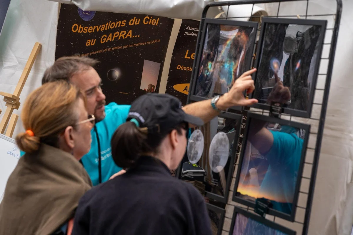 Visiteurs devant les photos du ciel exposées sur le stand du GAPRA