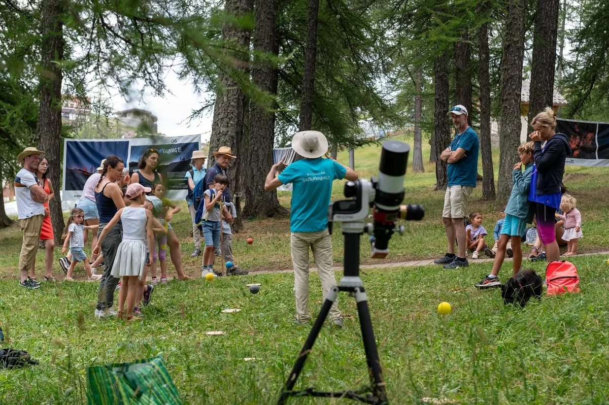 Un télescope pointé devant un groupe de familles sous les mélèzes à Valberg