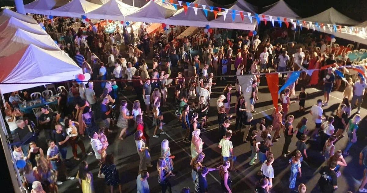 Foule dansant sous les fanions tricolores lors d'un bal des pompiers de village