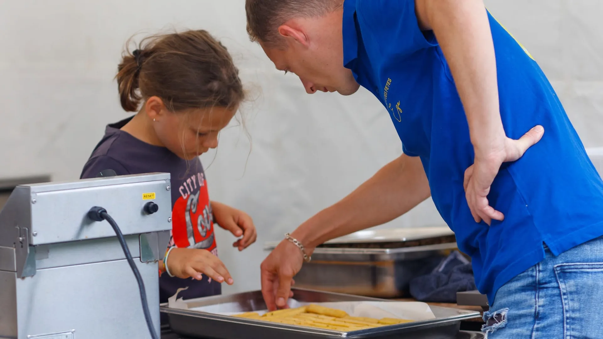Bénévole et enfant préparant les panisses à Èze