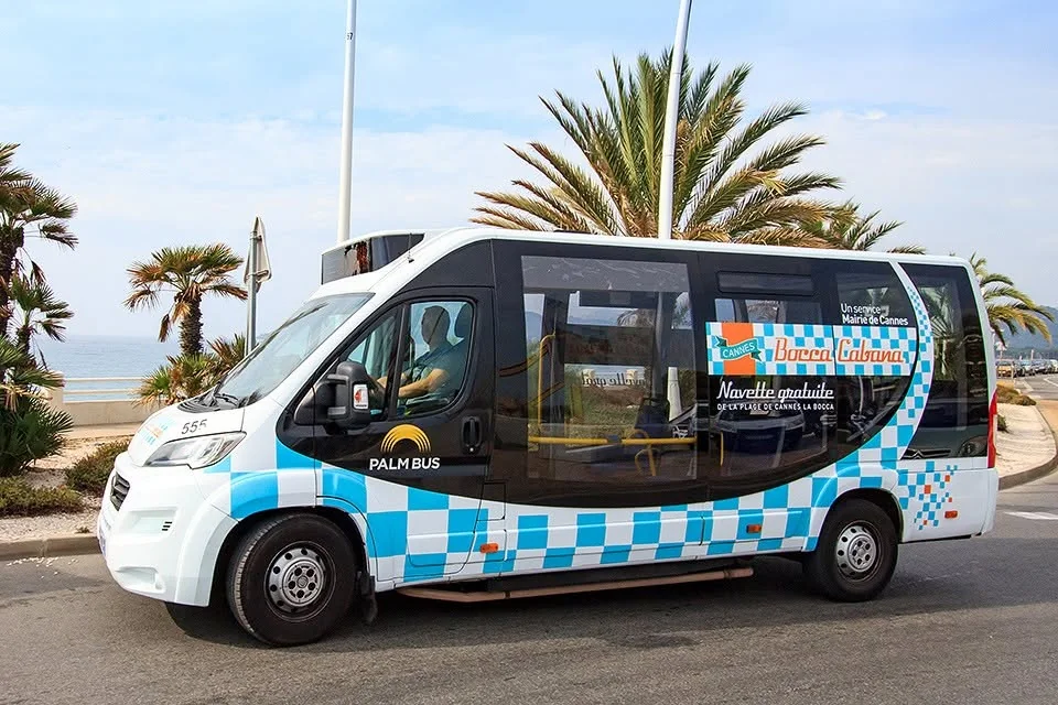 La navette BoccaCabana de Palm Bus, damier bleu et blanc, palmiers derrière