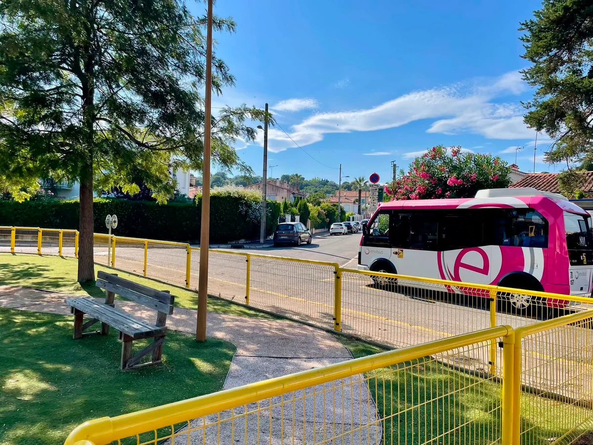 Une navette estivale rose Envibus dans une rue résidentielle sous le soleil