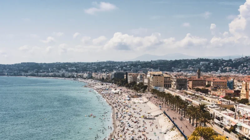 La Promenade des Anglais et la Baie des Anges à Nice vues d'en haut, plage bondée et palmiers un jour d'été