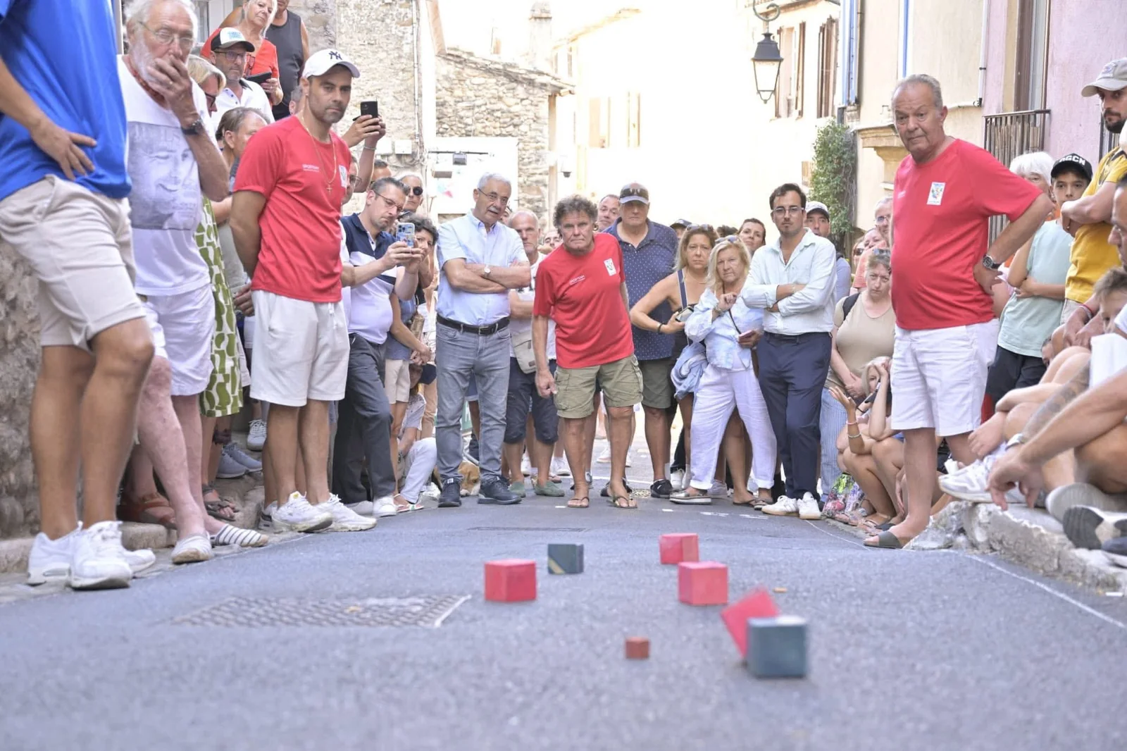 Une foule de spectateurs alignés le long d’une ruelle pendant une partie de boules carrées