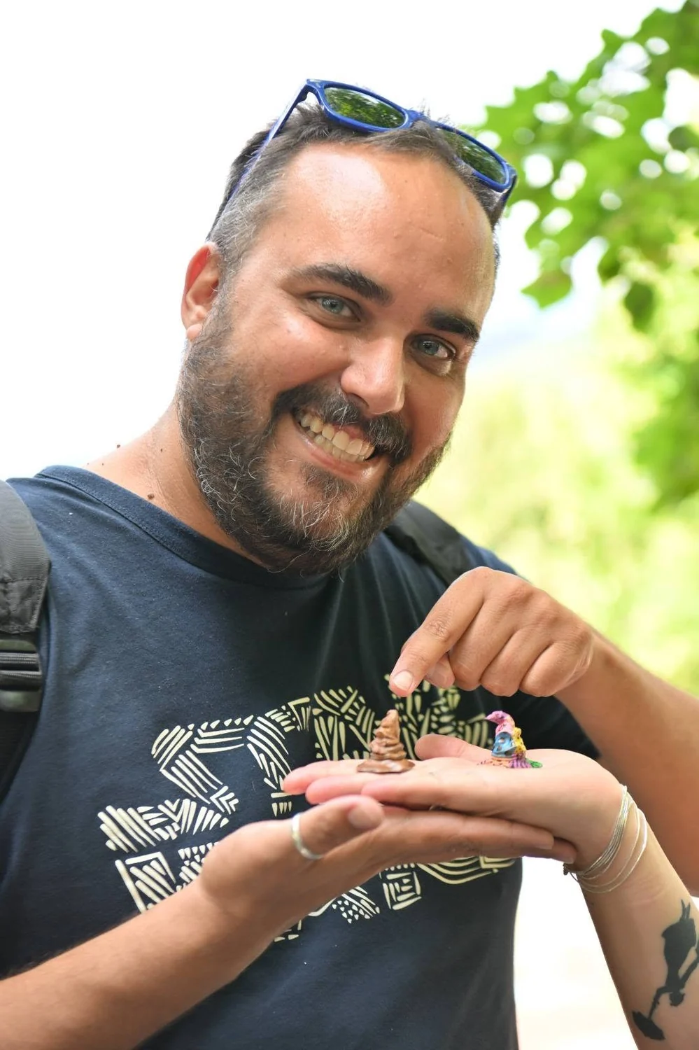 Un festivalier souriant présente deux figurines peintes au creux de sa main