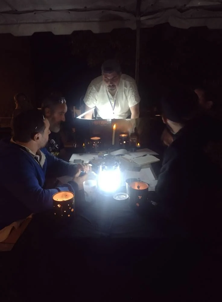 Des joueurs autour d’une table éclairée à la lanterne pendant une partie de nuit au festival de Clans