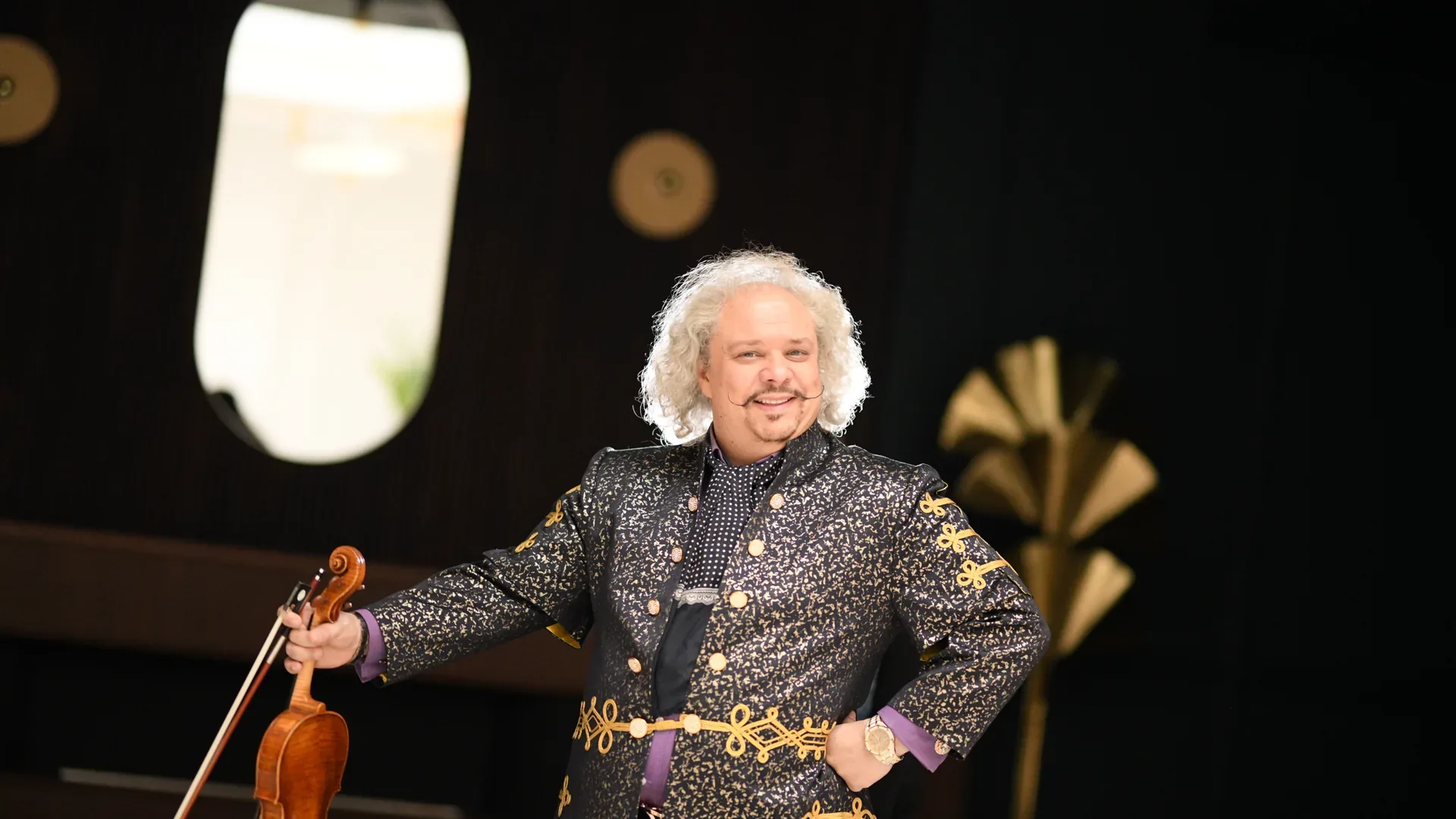 Roby Lakatos debout, violon à la main, en veste brodée