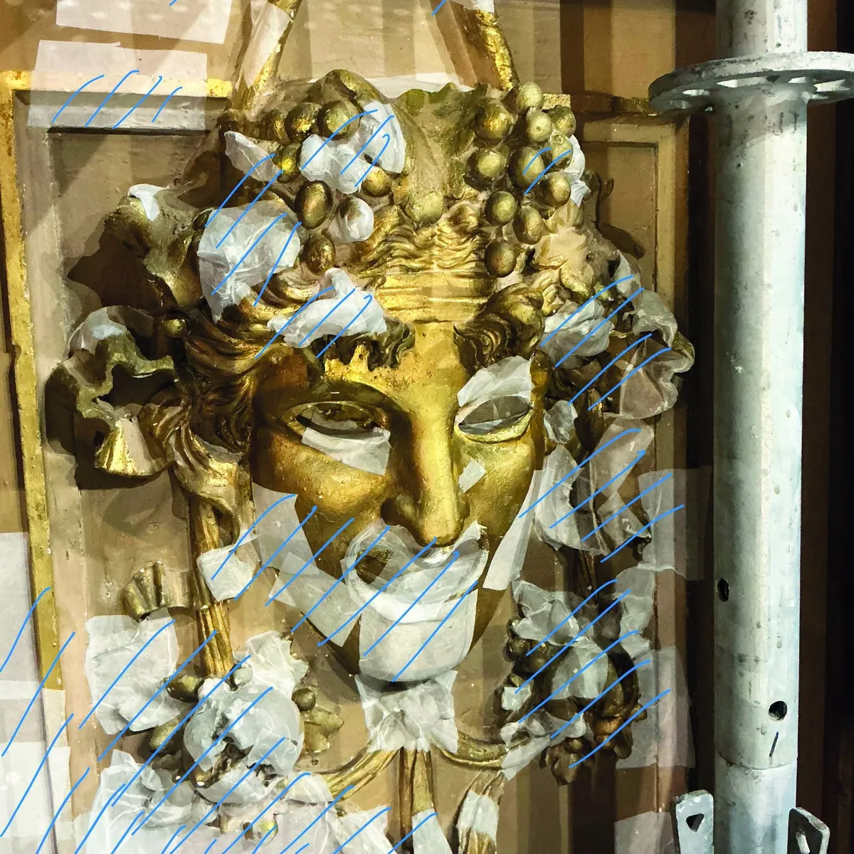 Un mascaron doré de l'Opéra de Nice protégé par du papier japonais, avec les traits bleus du relevé