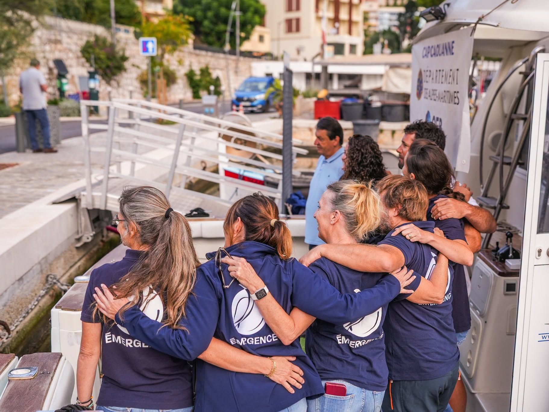 L’équipe d’Émergence s’enlace sur le pont du bateau, au port de Beaulieu