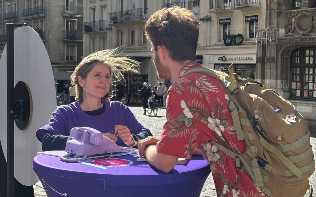 Une bénévole de l’Agence de la biomédecine accueille un passant à la table du bus, à Rouen