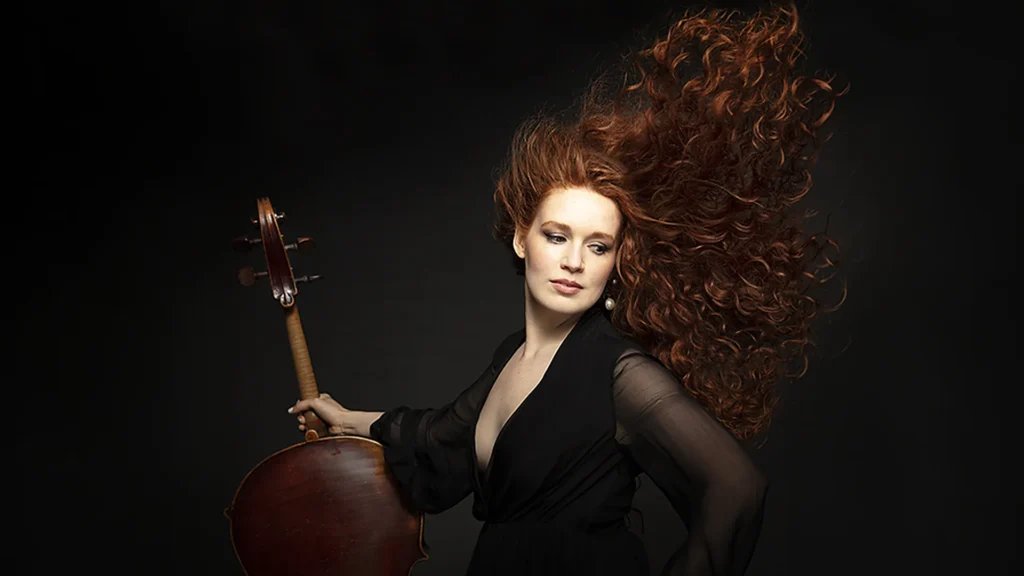 Camille Berthollet, cheveux au vent, tenant son violoncelle