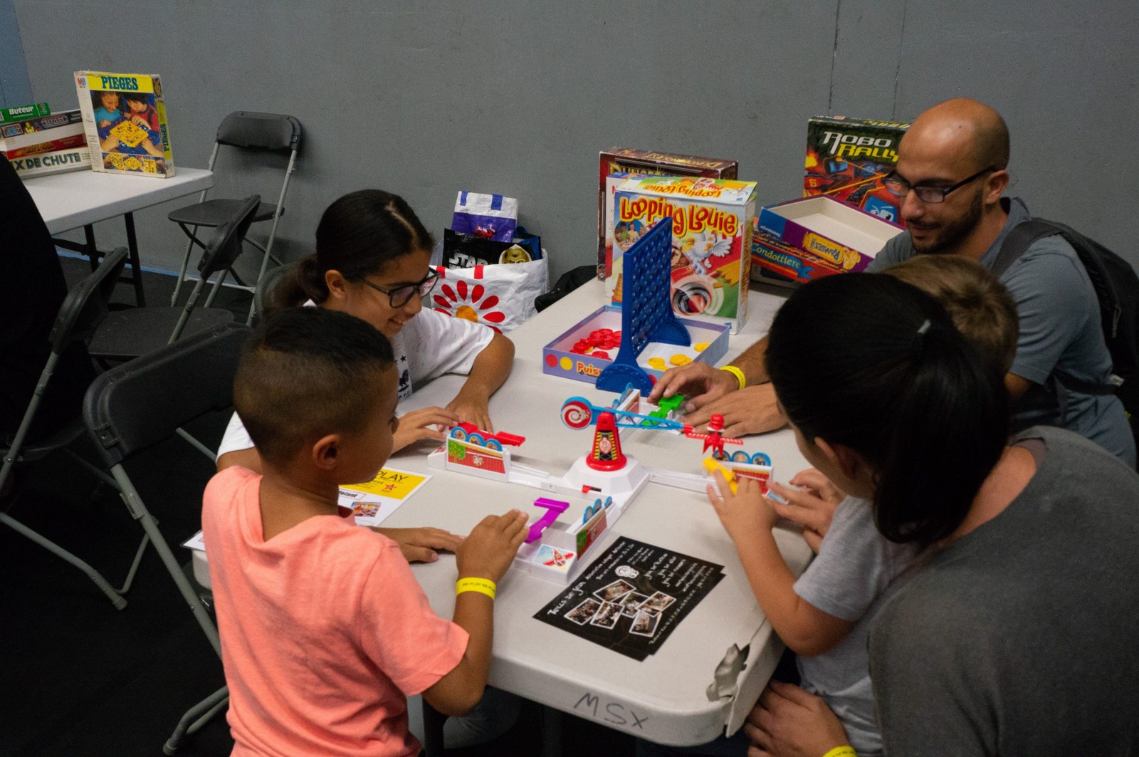 Enfants et adultes autour d'un jeu de société ancien posé sur une table