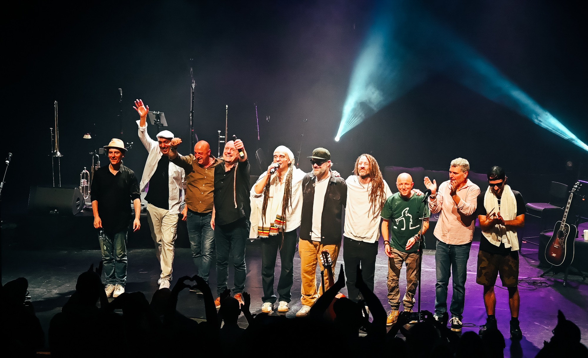 Les artistes du collectif Ensemble !!! alignés sur scène, les bras levés, face au public
