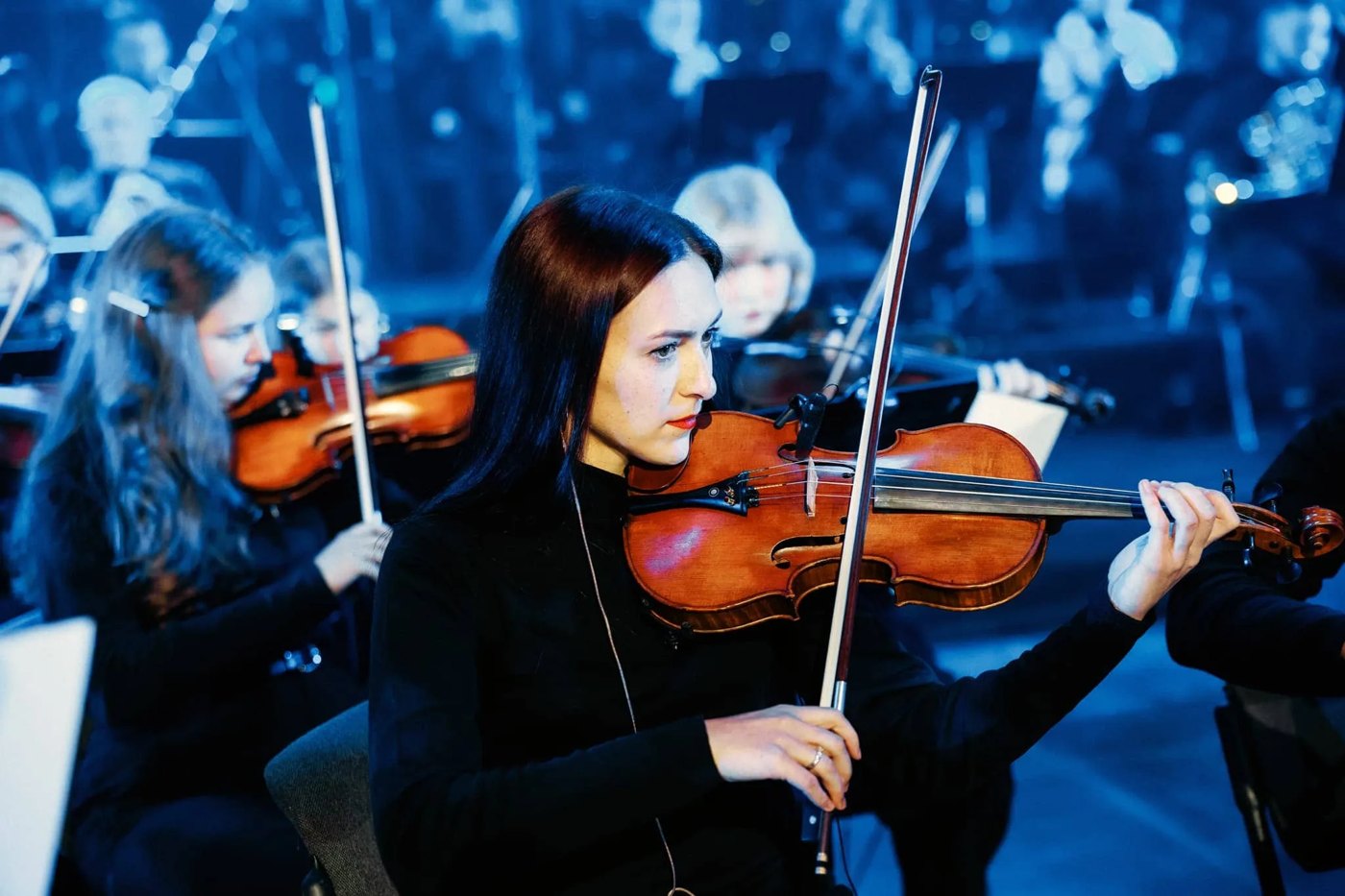 Violonistes de l'orchestre sur scène sous les lumières bleues